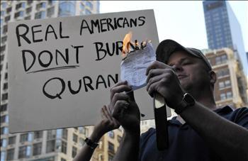 أميركي يحرق صفحات من القرآن في نيويورك فيما يرفع آخر لافتة كتب عليها: الأميركيون الحقيقيون لا يحرقون القرآن»