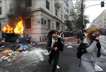 فتاتان تهربان من سيارة مشتعلة خلال الاشتباكات في أثينا أمس 