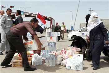 سوريون مقيمون في الأردن يعدون مساعدات إنسانية عند معبر جابر الحدودي مع سوريا لمحاولة نقلها إلى الداخل أمس 