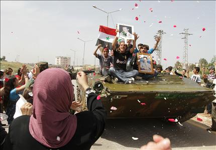 سوريون يرشون الورود على آليات للجيش خلال انسحابه من درعا أمس (أ ف ب) 