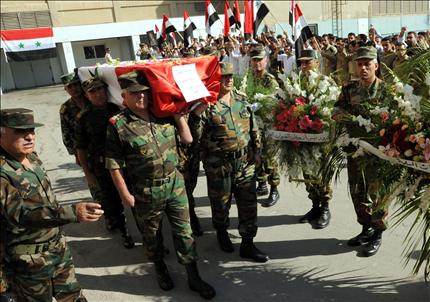 جنود سوريون يحملون جثمان زميل لهم من مستشفى دمشق أمس (أ ف ب)