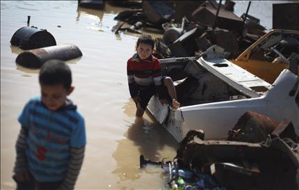 طفلان فلسطينيان بين المخلفات الصناعية في منطقة أغرقتها مياه الأمطار في وسط قطاع غزة الأحد الماضي (أ ب أ) 