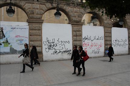 تونسيات يمررن الى جانب حائط في تونس كتبت عليه شعارات تنادي بالحرية والديموقراطية («السفير») 