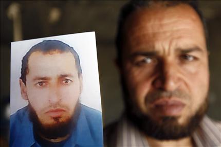 التونسي مختار مارس يحمل امس صورة شقيقه حسين الذي قتل في حمص (رويترز) 