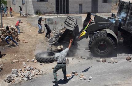 متظاهرون فلسطينيون ضد الاستيطان يرشقون الحجارة على جرافة الاحتلال في قرية كفر قدوم قرب نابلس في الضفة الغربية أمس (ا ف ب) 