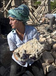 ناشطة تساعد فلسطينيين على إعادة بناء منازلهم التي دمرها الاحتلال في قرية في القدس المحتلة أمس (أ ف ب) 
