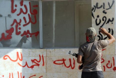 مقاتل من «شورى طالبان» يكتب شعارات اسلامية قرب معبر باب الهوى (بولنت كوليك - أ ف ب) 