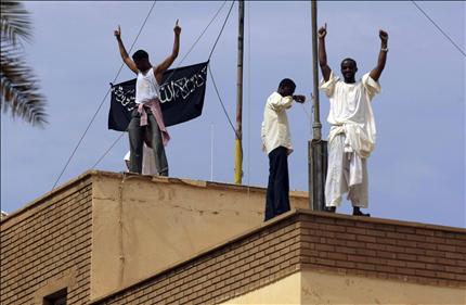 سودانيون يرفعون علماً أسود كُتبت عليه الشهادة فوق مبنى السفارة الألمانية في الخرطوم أمس (رويترز) 
