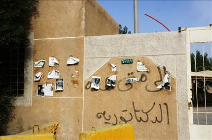  صور معتقلين وشعار «إلى متى هذه الديكتاتورية» على أحد جدران القطيف. («السفير») 