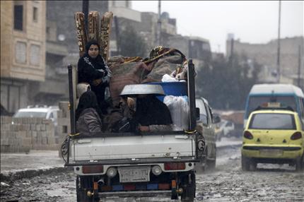  امرأة تجلس في شاحنة خارجة من حلب أمس (رويترز) 