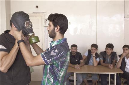 طالب في جامعة حلب يعطي دروساً في استخدام الأقنعة الواقية من الغاز في شمال مدينة حلب أمس الأول (أ ف ب)