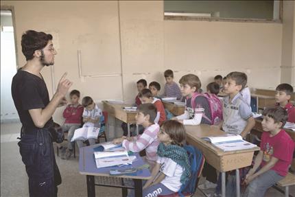 احد مسلحي المعارضة يعلم الاطفال في مدرسة في حي سيف الدولة في حلب في 30 ايلول الماضي (ا ف ب) 