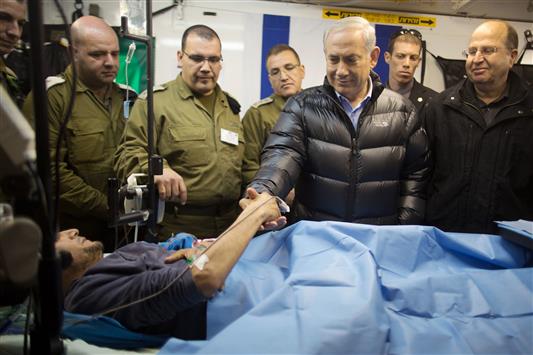 نتنياهو يصافح مسلحاً سوريا في مستشفى اسرائيلي في الجولان المحتل امس (رويترز)
