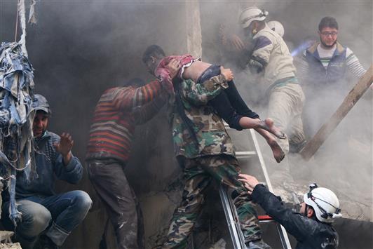سوريون ينقذون فتى من تحت حطام أحد المباني المدمرة في حي الشعار في حلب أمس (رويترز)