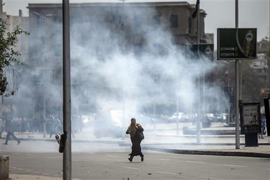 امرأة تهرب من قنابل الغاز المسيلة للدموع خلال اشتباكات بين الشرطة المصرية وطلاب من "الاخوان" امام جامعة القاهرة امس (ا ف ب)
