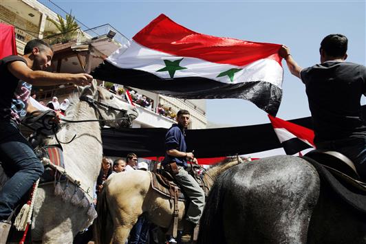 دروز من الجولان يحملون علم سوريا خلال احتفالات الجلاء في مجدل شمس امس (رويترز)