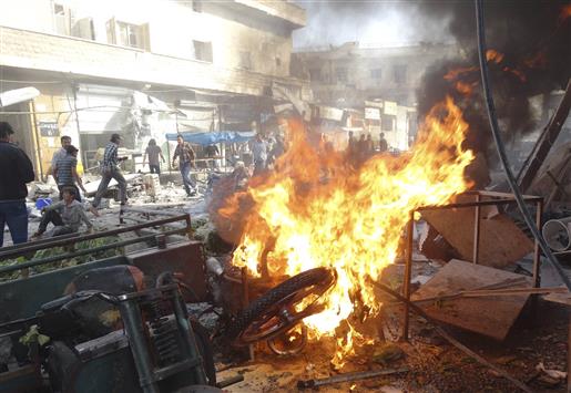 شبان يهرعون لاطفاء حريق ونقل الضحايا بعد غارة جوية على سوق في بلدة الاتارب في ريف حلب امس (رويترز)