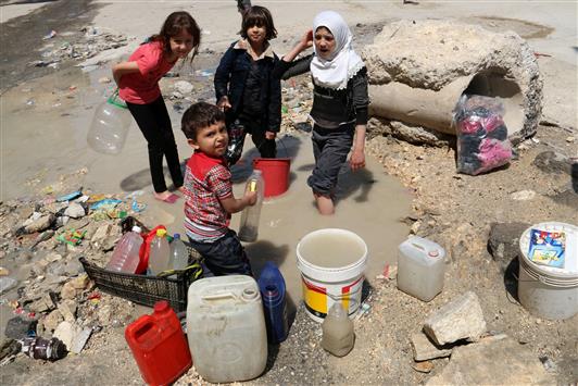 اطفال يملأون الدلاء بالماء من حفرة قرب الطريق في منطقة يسيطر المسلحون عليها في حلب امس (ا ف ب)
