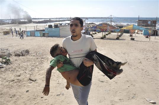 فلسطيني يحمل جثة طفل استشهد في غارة على شاطئ غزة أمس (رويترز)