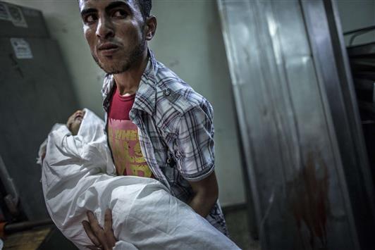 شاب يحمل جثة طفلة استشهدت في العدوان الاسرائيلي على غزة في مستشفى كمال عدوان في بيت لاهيا أمس (ا ف ب)