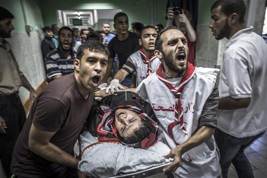 مسعفون يهرعون بشاب إلى المستشفى بعد إصابته في قصف الاحتلال الإسرائيلي لمدرسة «الأونروا» في غزة امس (ا ب ا)