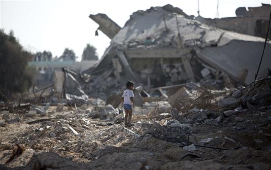 طفل يسير فوق مبانٍ دمرها الاحتلال الاسرائيلي في حي الشجاعية في غزة امس (ا ف ب)