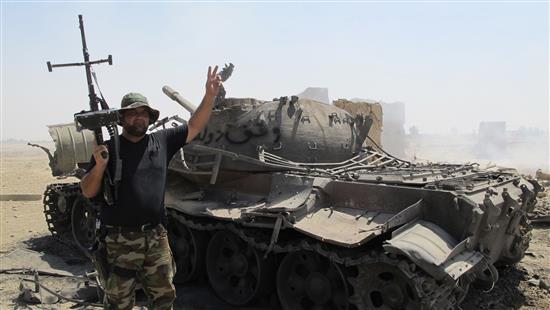 أحد عناصر قوات الأمن العراقية قرب حطام دبابة تابعة لـ"داعش" في بلدة آمرلي، أمس. (رويترز)