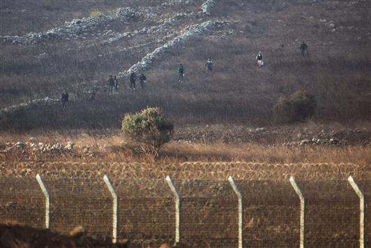 مسلحون من "جبهة النصرة" يسيرون امس قرب السياج الذي وضعته اسرائيل بين الجولان المحتل والقنيطرة (ا ف ب)