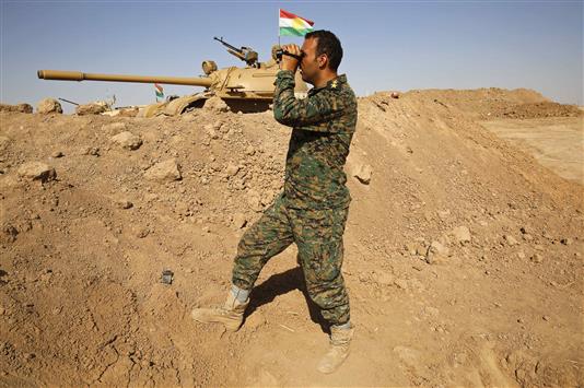 مقاتل من «البشمركة» يرصد نقاط القصف الذي يطال مواقع تنظيم «داعش» عند الخط الأمامي المؤدي إلى الموصل في خازر، أمس (رويترز)
