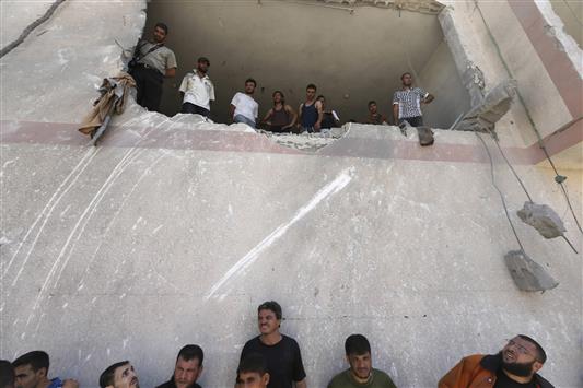 فلسطينيون يقفون في منزل دمره الاحتلال الإسرائيلي في بيت لاهيا في شمال قطاع غزة أمس (رويترز)