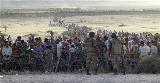جنديان تركيان يمنعان سوريين فروا من هجوم «داعش» من العبور الى الاراضي التركية امس (رويترز)