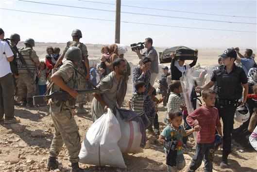 سوريون فروا من هجوم «داعش» يدخلون إلى تركيا أمس (رويترز)
