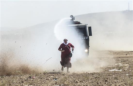 مدفع مياه تركي يطارد إمرأة كردية عند الحدود التركية ـ السورية في قرية سوروك في محافظة أورفة جنوب شرق تركيا أمس (أ ف ب)