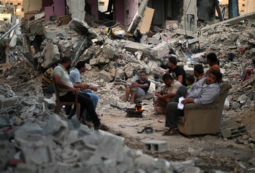 فلسطينيون يعدّون القهوة وسط المنازل المدمّرة في غزة أمس (رويترز)