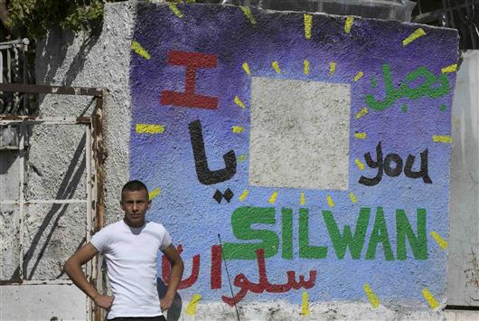 فلسطيني يقف إلى جانب جدار كتب عليه «أحبك يا سلوان» حيث المنزل الذي احتله المستوطنون في القدس المحتلة أمس (رويترز)