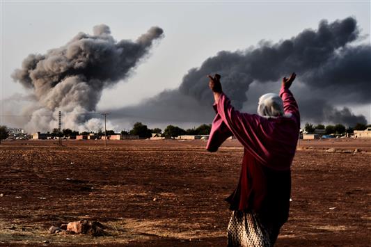 امرأة تراقب الغارات الجوية على عين العرب امس (ا ف ب)