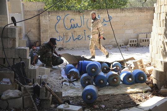 جنديان سوريان يتفحصان «اسطوانات متفجرة» في مورك في ريف حماه امس (رويترز)