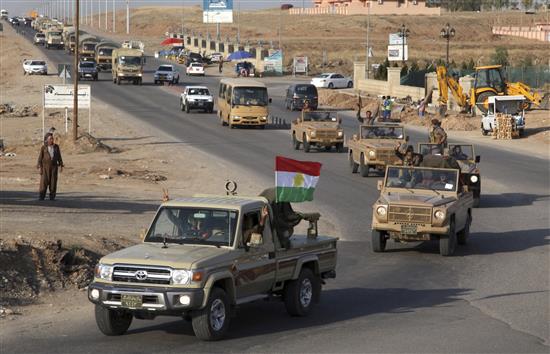 آليات عسكرية تنقل أسلحة وعناصر من «البشمركة» الكردية العراقية خلال انتقالهم من دهوك إلى تركيا ومنها إلى عين العرب أمس (رويترز)
