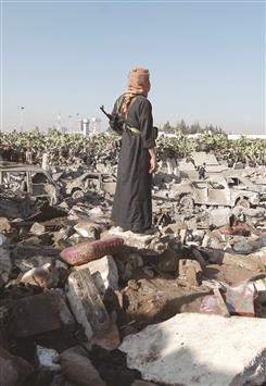 يمني يقف فوق الحطام الذي خلفته الغارات الجوية السعودية قرب مطار العاصمة صنعاء أمس