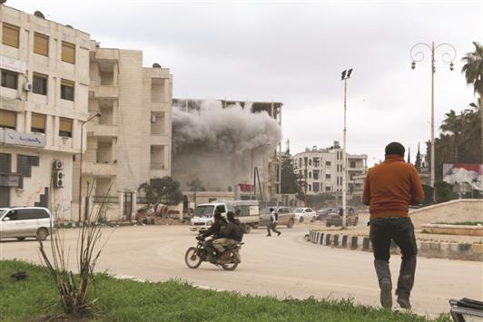 دخان يتصاعد من مبنى تعرض للقصف في ادلب امس الاول (رويترز)