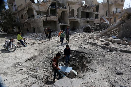 سوريون يتفقدون حفرة جراء غارة جوية في حلب أمس (ا ف ب)