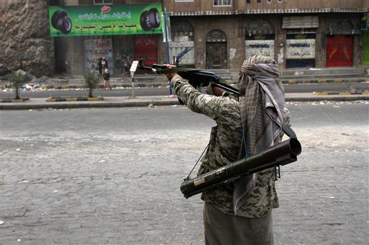 عنصر من ميليشيات هادي يرفع سلاحه في أحد شوارع تعز أمس الأول (أ ف ب)