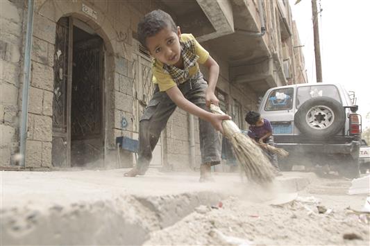 طفلان يمنيان يعملان على تنظيف الشوارع بعد توقف شاحنات القمامة عن العمل جراء النقص الحاد في الوقود، في صنعاء، أمس (أ ف ب)