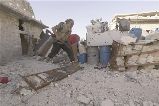 مسلح يركض خلال الاشتباك مع القوات السورية في حندرات في ريف حلب امس (رويترز)