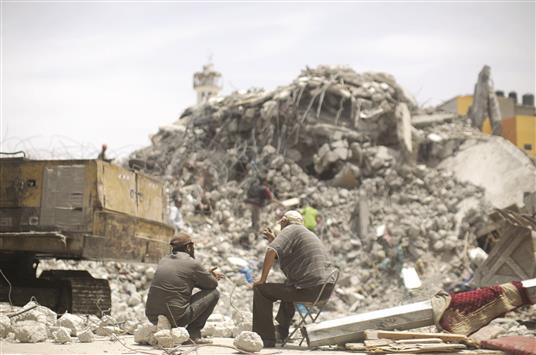 فلسطينيان يراقبان عملية هدم منازل في غزة امس (ا ف ب)