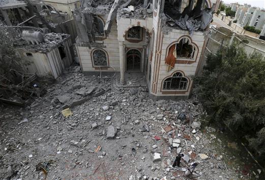 يمنيان يسيران بالقرب من مبنى مدمر جراء الغارات الجوية في العاصمة صنعاء، أمس (رويترز)