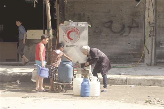 سوريون يعبئون غالونات ماء في حلب امس الاول (رويترز)