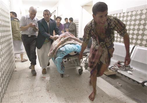 يمنيون يسعفون رجلاً أصيب في التفجيرين اللذين استهدفا مسجداً في صنعاء، أمس (أ ف ب)