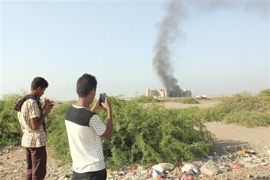 شخصان يصوران فندق القصر في عدن، الذي تعرض لتفجير انتحاري تبناه «داعش»، أمس (أ ب أ)