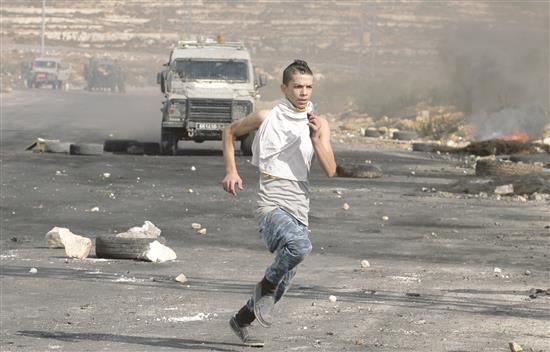 شرطة الاحتلال تلاحق فلسطينياً قرب مدينة رام الله في الضفة الغربية المحتلة، أمس (أ ف ب)